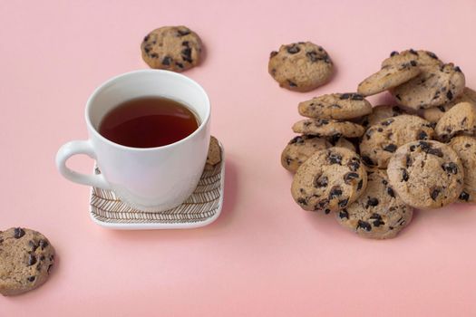 a cup of tea and a lot of cookies on a pink background. Overeating concept, sweet tooth. High quality photo