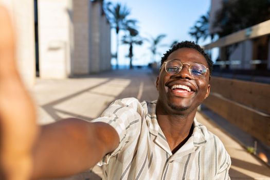 Happy young black man with glasses taking selfie looking at camera. Lifestyle concept.