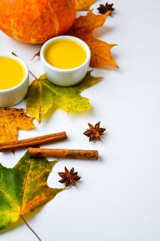 Autumn food. Pumpkin puree soup, leaves. Autumn harvest, pumpkins, leaves on grey as abstract background. Thanksgiving day. Seasonal food. Vegetarian