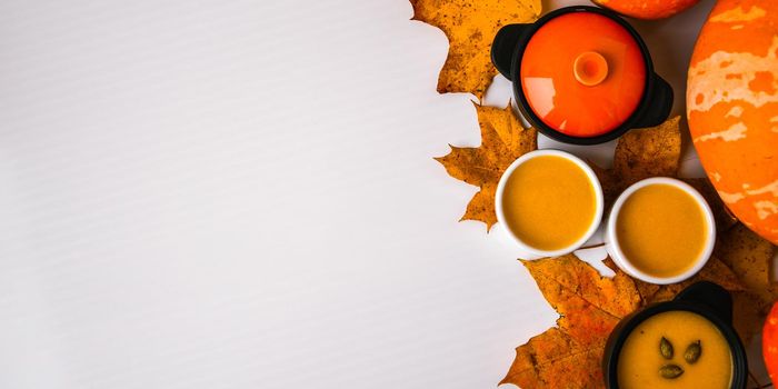 Autumn food. Frame of pumpkin puree soup, leaves. Top view. Autumn harvest, pumpkins, leaves on grey as abstract background. View from above. Thanksgiving day. Flat lay. Copy space
