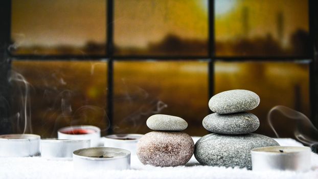 Zen concept, spa pebbles stones and burning aroma candles smoke on blurred background, Treatment aromatherapy and massage, copy space for text