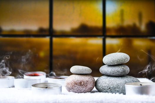 Zen concept, spa pebbles stones and burning aroma candles smoke on blurred background, Treatment aromatherapy and massage, copy space for text