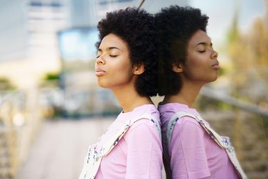 Thoughtful African-American woman with her eyes closed in a relaxed attitude on an urban background.