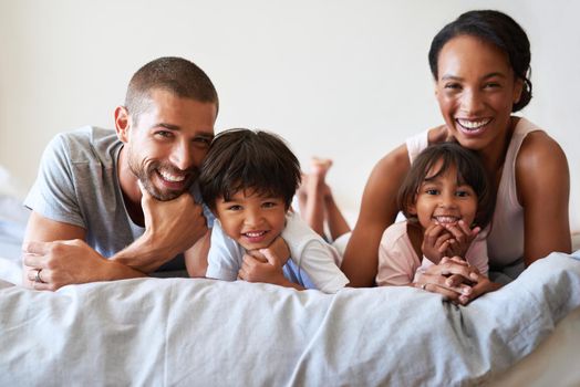Portrait of a beautiful young family of four bonding and spending time together in bed at home.
