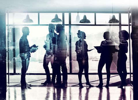 Full length shot of coworkers standing in front of a window superimposed over a cityscape.