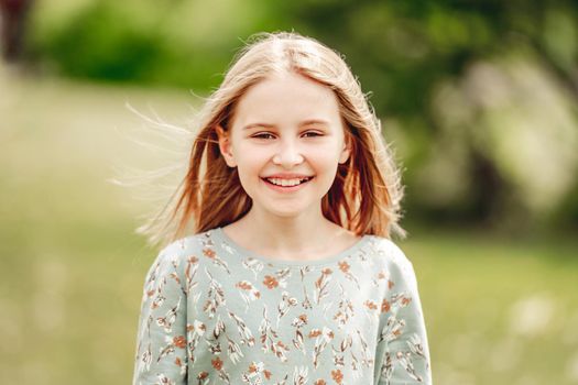 Little girl smiling in sunny spring day outdoors portrait. Cute child kid at nature