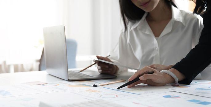 Two young Asian businesswoman discuss investment project working and planning strategy. Business people talking together with laptop computer at office..