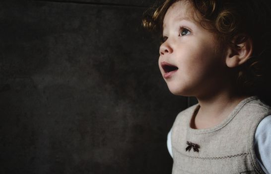 Beautiful young girl looking away against a dark moody background