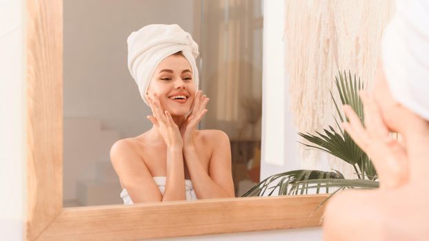 A young smiling woman takes care of her skin and hair after a shower. Spa treatments at home, skin care. Web banner.