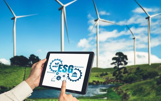 Green business transformation for environment saving and ESG business concept. Businessman using tablet to set corporate goal toward environmental friendly management and alternative clean energy use.