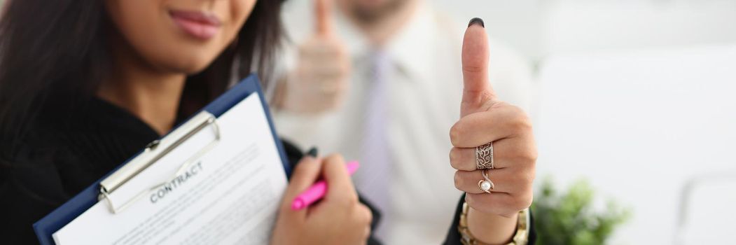 A woman holds a contract and shows an ok gesture, close-up, blurry. Meeting to sign a cooperation agreement