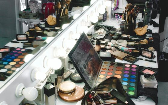 Rabat / Malta - December 8 2019: Makeup products, accessories and tools on a salon table in front of a light mirror