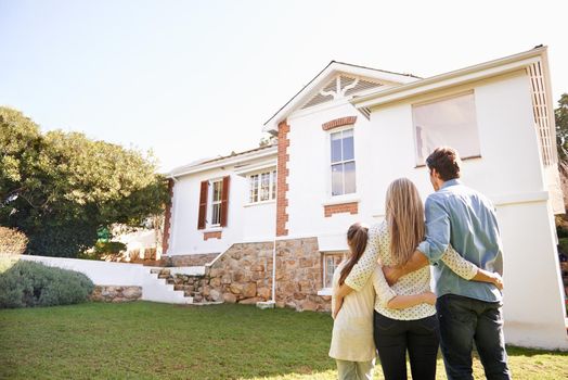 A family standing outdoors admiring their new home.