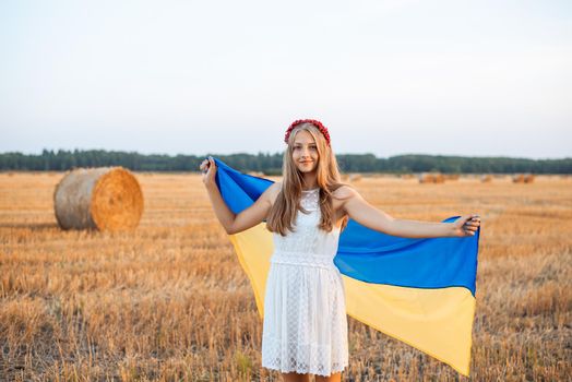 Girl with Ukrainian flag and bright hair hoop outdoors in the countryside