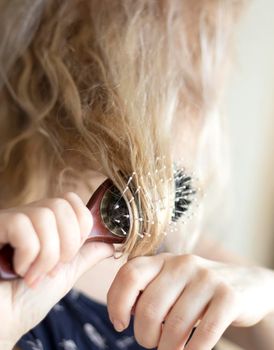 selective focus. blond combing wet and tangled hair. Young woman combing her tangled hair after shower. Daily preparation for looking nice. High quality photo