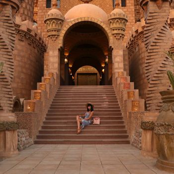 young girl on the background of the El Mustafa Mosque in the Old City of Egypt. woman sits on the steps of a mosque. Travel to Egypt concept. An ancient mosque in the tourist city of Sharm El Sheikh