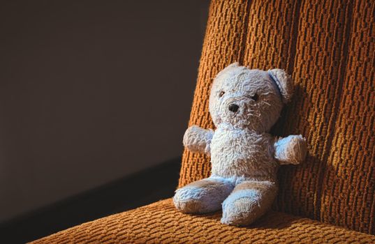 Traditional blue soft toy teddy bear sat alone on a chair