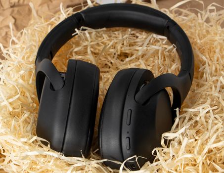 black stereo headphones in gift tinsel, paper shavings. High quality photo