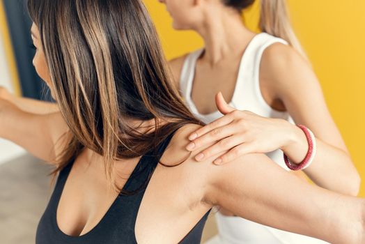 The hand of a female trainer, helps a woman to stand in a pose of a warrior. Close up. Happy yoga class with a trainer. Exercise control.