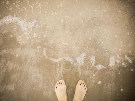 barefoot on brawn beach with bublles of wave holiday idea for relax background