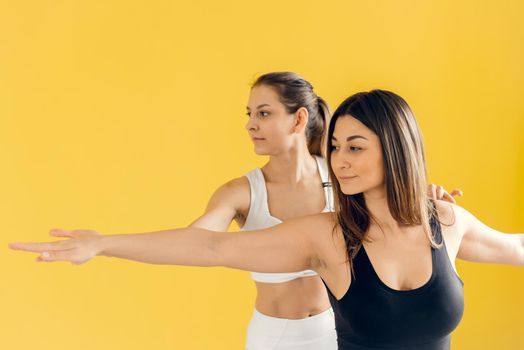 Beautiful woman practicing yoga, conducting a training session with female students, showing the correct execution of Virabhadrasana exercise, warrior pose. Training concept