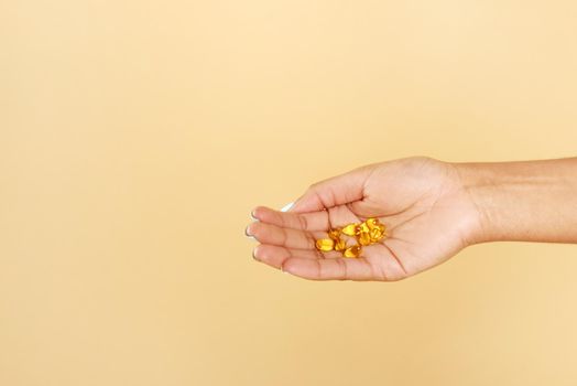 Close up of afro american woman's hands taking beauty supplements for glowing skin. A black woman holds vitamins c in her hands