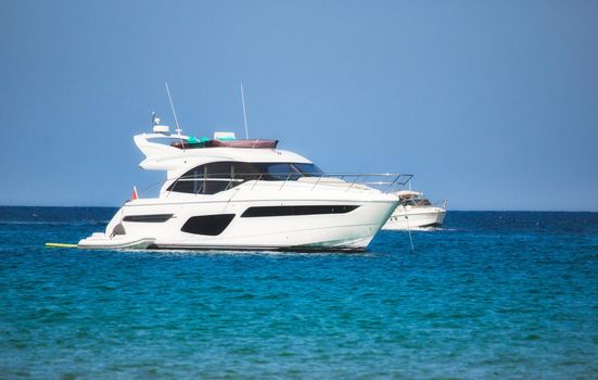 A luxury yacht sailing on the sea with clear blue sky and horizon visible in the background