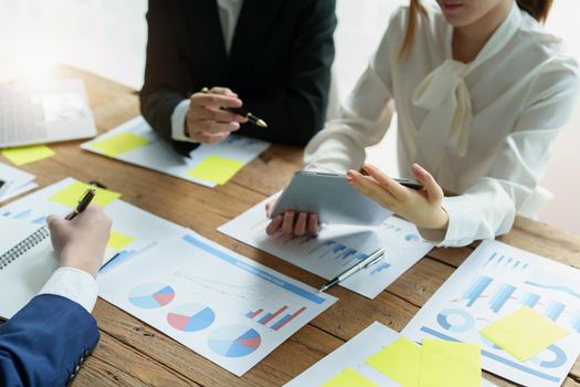 Businesswoman holding pen pointing at tablet to discuss marketing strategy summaries with colleagues in meetings, teamwork, investment planning.