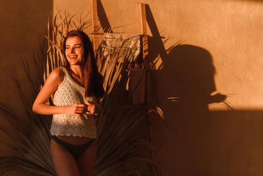 Young woman at home in the bathroom on a background of tropical shadows. Sunlight, shadows of tropical palm leaves