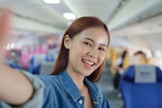 Travel, tourism business, portrait of a woman using her phone selfie on an airplane to post a profile picture of herself.