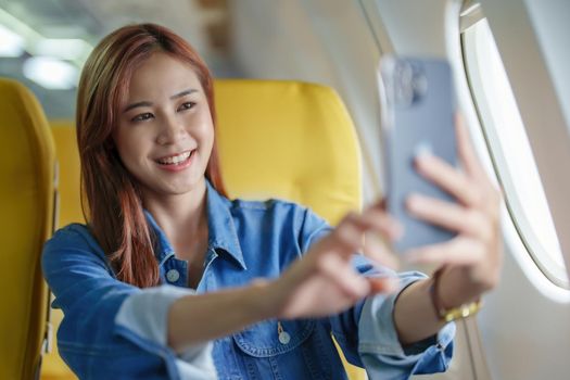 Travel, tourism business, portrait of a woman using her phone selfie on an airplane to post a profile picture of herself.