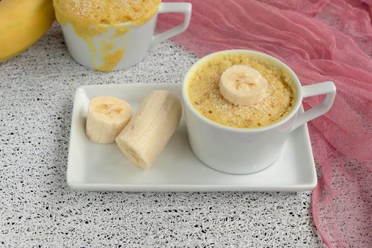 cupcake in a mug with banana pieces. Banana cupcake on a light background. The concept of a dessert in the microwave. bananas cake. High quality photo