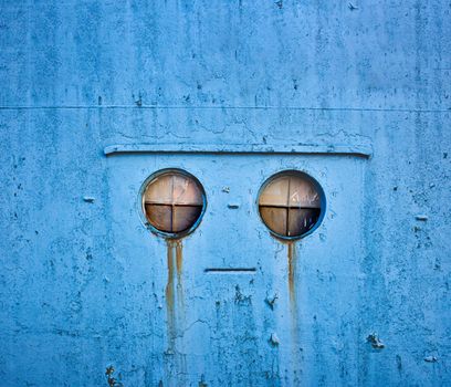 A robotic mechanical face shedding tears in a blue metallic industrial wall