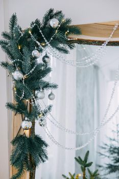 Decorated mirror and live Christmas tree with lights. New year's interior, festive atmosphere, decor, garlands, gifts.