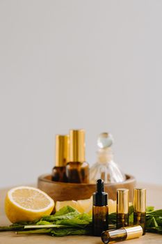 Essential oil in bottles with lemon and mint fragrance lying on a wooden surface.