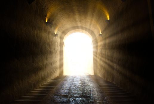 A bright yellow glowing light breaking through at the end of a dark tunnel