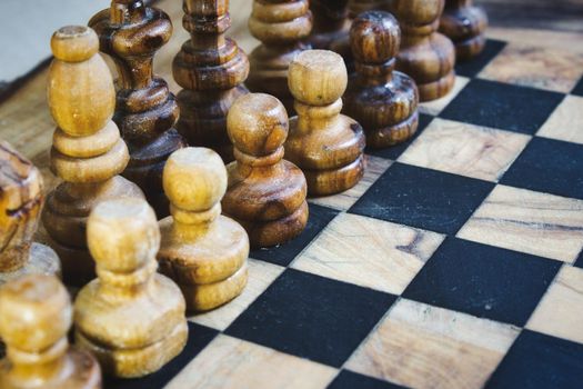 Olive wood chess pieces lined up on a wooden chequered board
