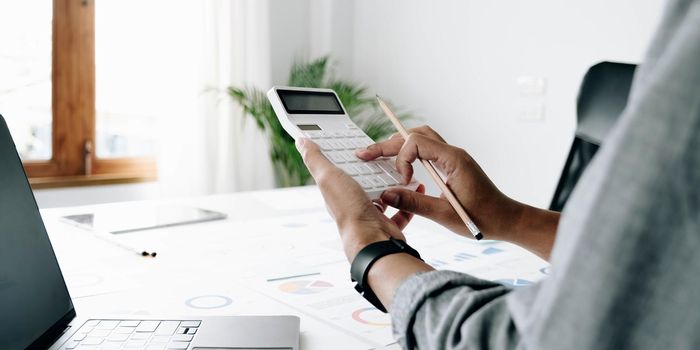 Close up businessman hand using calculator and working with laptop calculate about finance accounting at coffeeshop outdor.finance accounting concept.