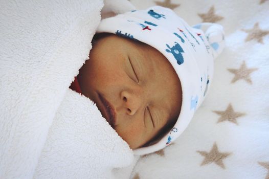 A newborn baby sleeping, wrapped up in swaddling blanket