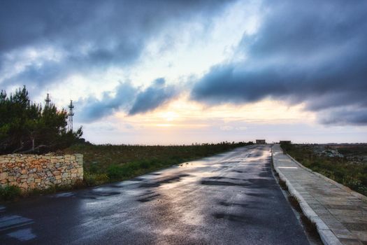 An empty road with a dramatic sky with moody clouds in the background