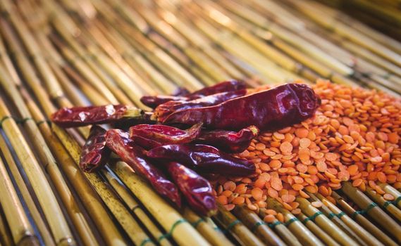 Chili peppers (Capsicum annuum) and red lentils on a bamboo mat