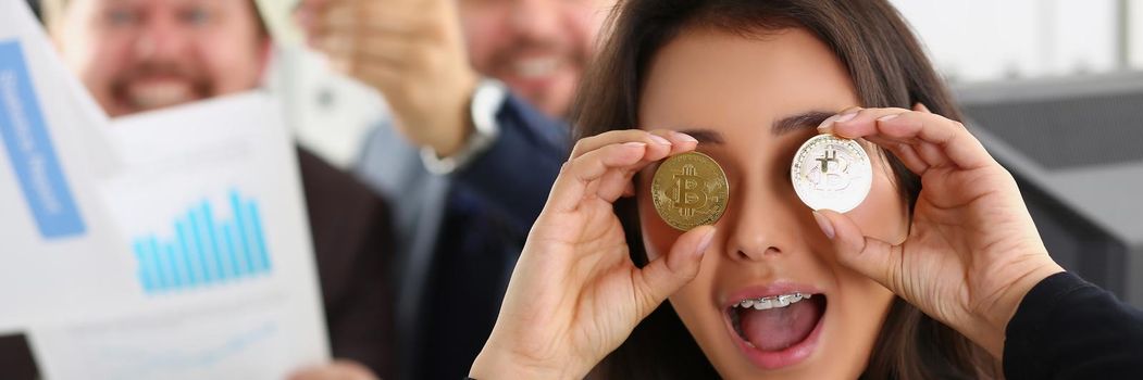 Woman shows coins bitcoins, close-up, blurry. Happy people with money in their hands. Profit from cryptocurrency