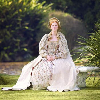 Portrait of a noble woman sitting outdoors on palace grounds.