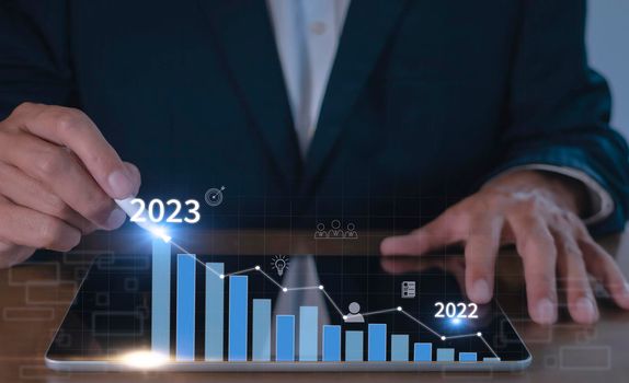 Businessman hand using tablet with creative glowing arrow and stock chart. Hand of businessman use tablet analysis stock market graph growth and increase of chart positive indicators.