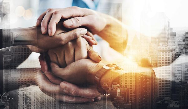 Cropped shot of a group of unrecognizable businesspeople sitting in the boardroom with their hands in a huddle.