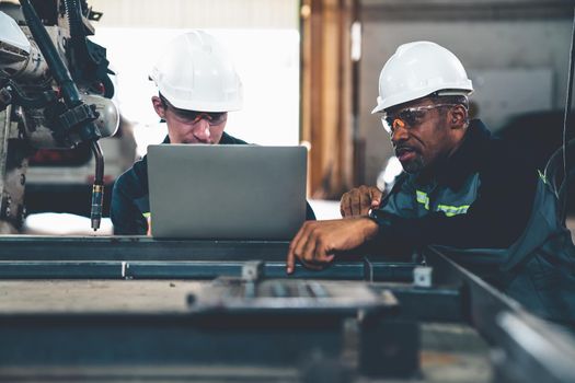 Factory workers working with adept robotic arm in a workshop . Industry robot programming software for automated manufacturing technology .