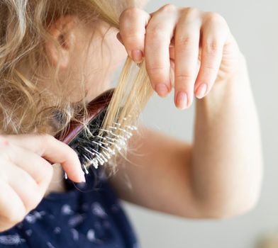 selective focus. blond combing wet and tangled hair. Young woman combing her tangled hair after shower. Daily preparation for looking nice. High quality photo