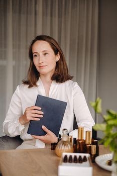 portrait of a smiling girl-woman sitting in an armchair. An aromatherapist in a white blouse is sitting in the office.