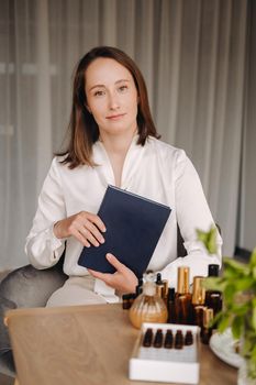 portrait of a smiling girl-woman sitting in an armchair. An aromatherapist in a white blouse is sitting in the office.