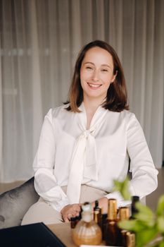 portrait of a smiling girl-woman sitting in an armchair. An aromatherapist in a white blouse is sitting in the office.